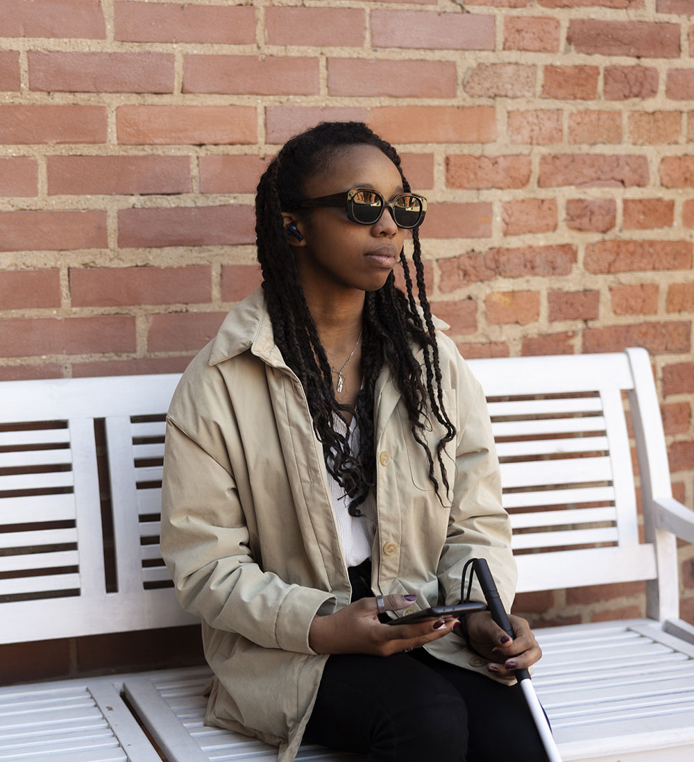 photo d'une femme de couleur noire, aveugle tenant un smartphone.
